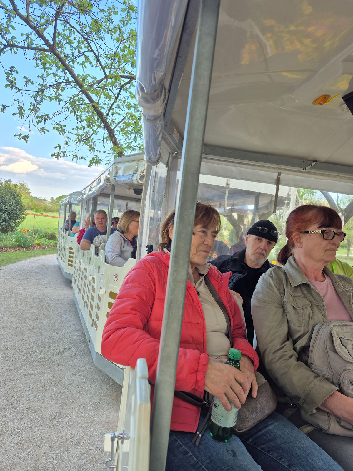 Člani društva sedijo v vagončkih vlakca med vožnjo po Arboretumu
