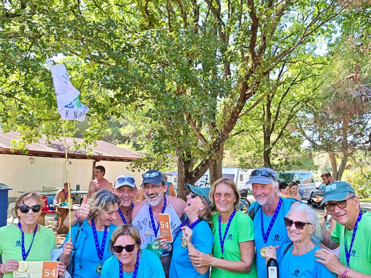 Ekipa Društva naturistov k naravi z medaljami in zastavo društva na igrah Alpe-Adria